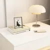 A white nightstand with a lamp, books, and a smartphone on top. Náhľad obrázku produktu