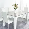 A dining table with white chairs and a vase of flowers. Voir les images du produit