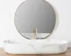 A close-up view of a marble-patterned sink with a gold faucet, set against a white wall and a round mirror. Náhľad obrázku produktu