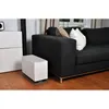A white humidifier is placed on a wooden floor next to a dark gray sofa with pillows. Produktbild-Vorschau