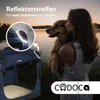 A woman is holding a dog next to a lake at sunset, with a dog carrier in the foreground. Produktbild-Vorschau