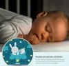 A baby sleeping next to a night light with a bunny design. Voir les images du produit