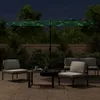 An outdoor patio scene at night with a double umbrella and seating. Produktbild-Vorschau