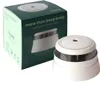 A white smoke alarm sits next to its dark green packaging box, both on a white background. Náhled obrázku produktu
