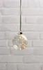 A clear glass ornament filled with fairy lights hangs against a white brick wall. Produktbild-Vorschau