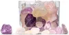 A clear glass container filled with colorful polished stones, with some stones scattered in front of the container on a white surface. Produktbild-Vorschau