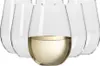 A set of six clear stemless wine glasses, with one glass filled with a pale yellow liquid. Náhled obrázku produktu