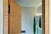 An open wooden door revealing a modern interior with plants and lighting. Podgląd zdjęcia produktu