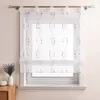 A transparent white curtain with a gray embroidered pattern hangs in front of a window. Produktbild-Vorschau