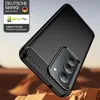 A black smartphone case with a carbon fiber accent is shown at an angle, resting on a textured, rocky surface. Produktbild-Vorschau