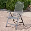 A metal folding chair is placed on a brick patio in front of a green bush. Produktbild-Vorschau