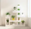 A white wooden plant stand filled with various potted plants, placed against a light-colored wall. Náhled obrázku produktu