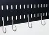 A close-up view of a black pegboard with white hooks attached. Anteprima dell’immagine prodotto