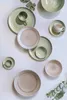 A collection of ceramic plates and cups arranged on a wall. Produktbild-Vorschau