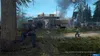 Two people are in a combat situation in a wooded area with a building and a tower in the background. Produktbild-Vorschau