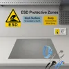 An ESD protective mat and wrist strap are displayed on a desk with informational text and electrical outlets in the background. Produktbild-Vorschau