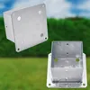 Two galvanized steel post bases are shown against a blurred background of green bushes and blue sky. Náhled obrázku produktu
