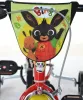 Close-up of the handlebars and front of a red children's tricycle with cartoon characters from the show Bing. Produktbild-Vorschau
