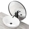 A white oval countertop sink with black faucets and drain, reflected in a round mirror, placed on a light wood-grain surface. Náhled obrázku produktu