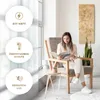 A woman is sitting in a chair reading a magazine in a well-lit room, with a decorative panel on the wall and a plant. Produktbild-Vorschau