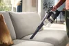 A person is using a cordless vacuum cleaner on a sofa. Náhľad obrázku produktu