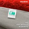 Close-up of the back of a red rug, showing the label and the anti-slip backing. Produktbild-Vorschau