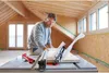A man is using a table saw in a room under construction. Voir les images du produit