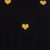 A close-up view of a black fabric with scattered golden heart shapes. Produktbild-Vorschau
