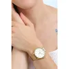 A woman's wrist wearing a gold watch with a white face. Produktbild-Vorschau