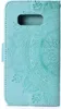 A close-up view of a teal flip phone case with an embossed mandala pattern. Produktbild-Vorschau