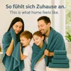 A family wrapped in teal towels, smiling and embracing. Produktbild-Vorschau
