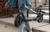 A person is carrying a folded electric scooter. Produktbild-Vorschau