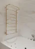 A gold towel warmer is mounted on a marble-tiled wall above a white bathtub. Podgląd zdjęcia produktu