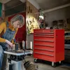 A woman is working in a workshop with tools and a red tool chest. Produktbild-Vorschau