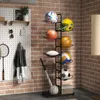 A multi-tiered storage rack filled with various sports balls and a helmet, placed against a brick wall. Podgląd zdjęcia produktu