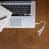 A top-down view of a laptop with a notebook and pen, and a USB hub connected to the laptop. Produktbild-Vorschau