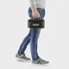 A person walking while holding a small black bag with a yellow logo. Produktbild-Vorschau
