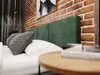 A bedroom scene with a bed, pillows, and a brick wall. Produktbild-Vorschau