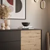 A modern dresser with wooden slatted doors, decorated with vases and books. Produktbild-Vorschau