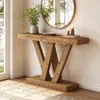 A rustic wooden console table with a V-shaped base is placed in a well-lit entryway or living room, next to a window and a round mirror. Podgląd zdjęcia produktu