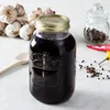 A Kilner jar filled with a dark red liquid, placed on a marble surface. Surrounding the jar are ingredients like garlic, peppercorns, and chili peppers, suggesting it might be used for preserving or making infusions. Podgląd zdjęcia produktu