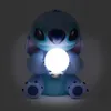 A blue Stitch figurine holding a glowing white orb in its hands, set against a dark background. Produktbild-Vorschau