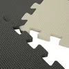 Close-up view of two interlocking puzzle mats, one gray and one beige, showing their textured surface and interlocking edges. Náhľad obrázku produktu