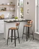 A kitchen island with two bar stools in front of it, with shelves and a window in the background. Náhled obrázku produktu