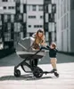 A mother and her child are outdoors with a stroller and a stroller board. Náhľad obrázku produktu