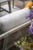 Close-up of a garden lounge set with a taupe rope-woven back and a light gray cushion. An orange cushion is visible in the background. Produktbild-Vorschau