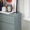 A close-up view of a gray shoe cabinet with decorative items on top, next to a window. Anteprima dell’immagine prodotto