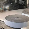 Two rolls of black foam insulation tape with white grid backing are placed on the floor of a van. Produktbild-Vorschau