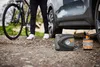 A person is using a portable tire inflator and sealant to inflate a car tire next to a bicycle. Produktbild-Vorschau