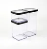 Two clear plastic food storage containers with black lids are shown against a white background. One container is taller than the other, and a smaller container is stacked on top of the shorter one. Produktbild-Vorschau